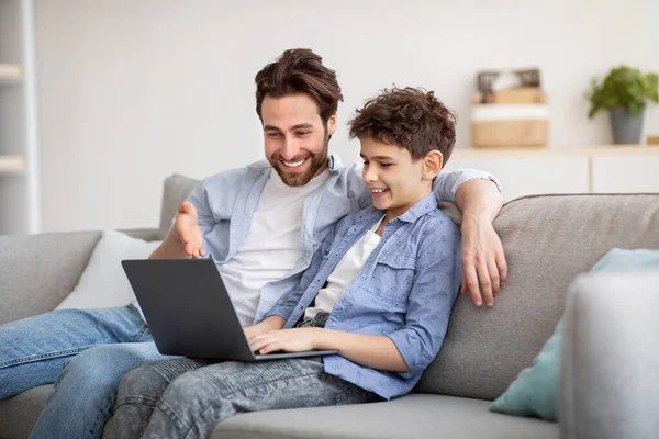 Jeune père et son fils préadolescent en utilisant un ordinateur portable ensemble, en regardant l'écran d'ordinateur, faire des achats en ligne — Photo