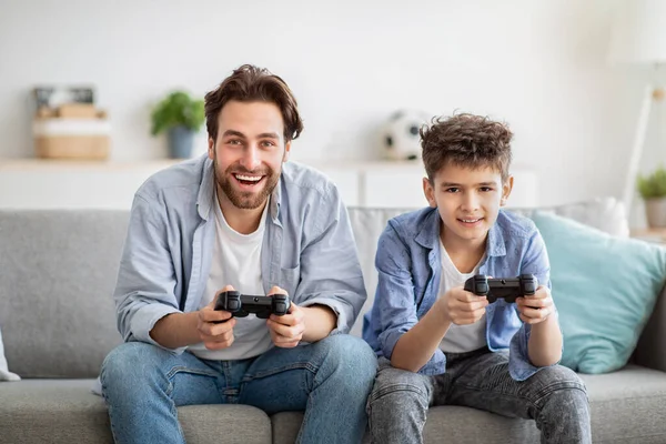 Lazer familiar masculino. Pai feliz e seu filho jogando videogames online e competindo, usando joysticks — Fotografia de Stock