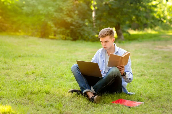 Fokuserad student Guy gör college läxor med bärbar dator och boka utomhus — Stockfoto