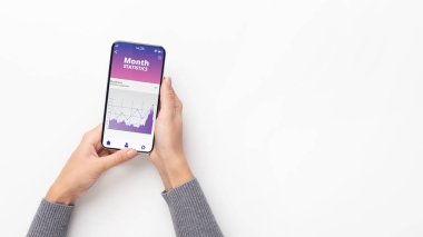 Ekranda grafikler ve diyagramlarla akıllı telefon tutan kadın eller