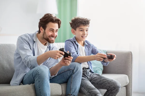 男の子は男の子です。喜びの父と10代の息子は、オンラインビデオゲームで互いに競合し、ジョイスティックを使用して — ストック写真