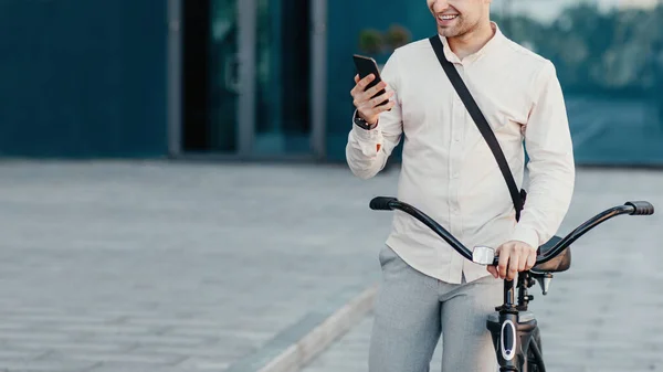 Jovem empresário elegante com smartphone na mão, com bicicleta — Fotografia de Stock