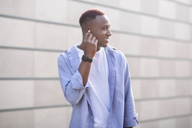 Kulaklıklı neşeli Afrikalı Amerikalı adam şehir sokaklarında yürürken en sevdiği müziği dinliyor.