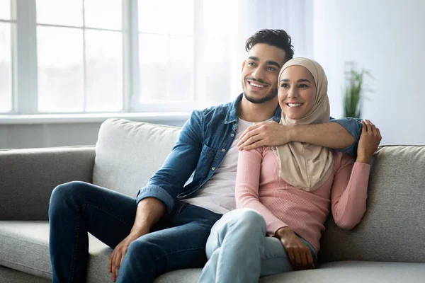 Positivo arabo coppia seduta su divano a casa — Foto Stock