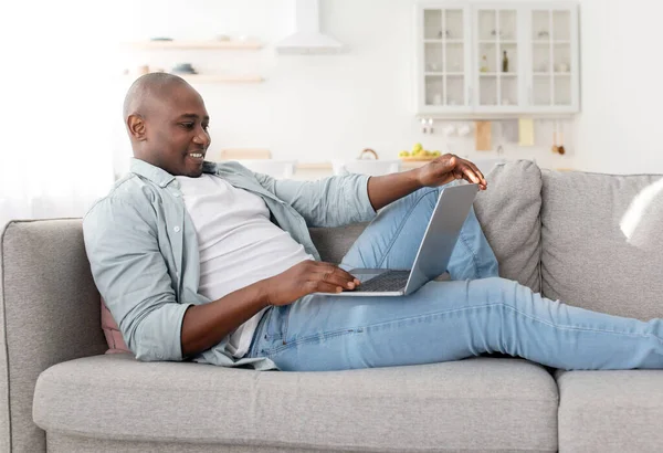 Happy middle-aged freelancer using modern laptop computer, having part-time job at home, sitting on sofa — Stock Photo, Image