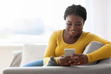 Mobil İletişim. Mutlu Afrikalı Amerikalı Kadın Evde Akıllı Telefondan Mesajlar Okuyor