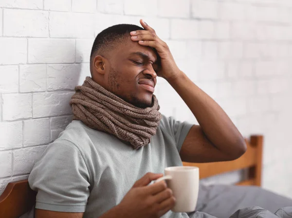 Afrikaanse man aanraken voorhoofd hebben koorts zitten in bed Indoor — Stockfoto