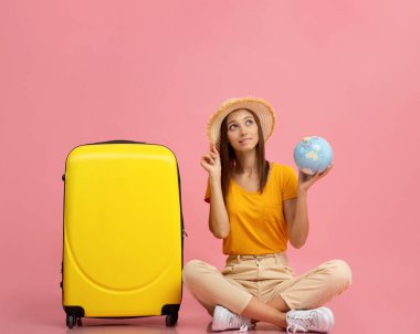 Kafası karışmış genç bir kadın, bavulun yanında oturuyor.