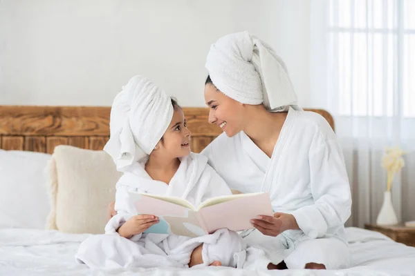 Madre e figlia in accappatoi libro di lettura — Foto Stock