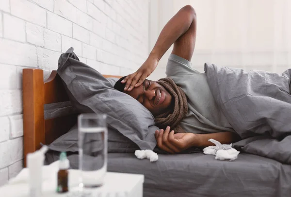 Enfermo chico teniendo dolor de cabeza severo acostado en la cama en casa — Foto de Stock