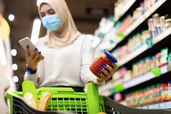 Süpermarkette telefon alan ve yemek tarayan Müslüman kadın.