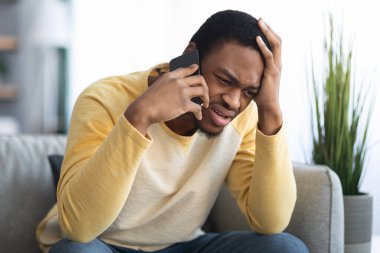 Üzgün siyahi adamın telefonda konuştuğu yakın plan.