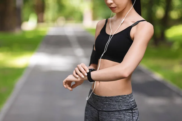 Mujer deportiva irreconocible configurar smartwatch fitness antes de correr en el parque — Foto de Stock