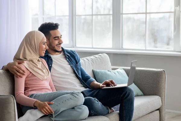 Glad ung muslimsk familj använder laptop tillsammans hemma — Stockfoto