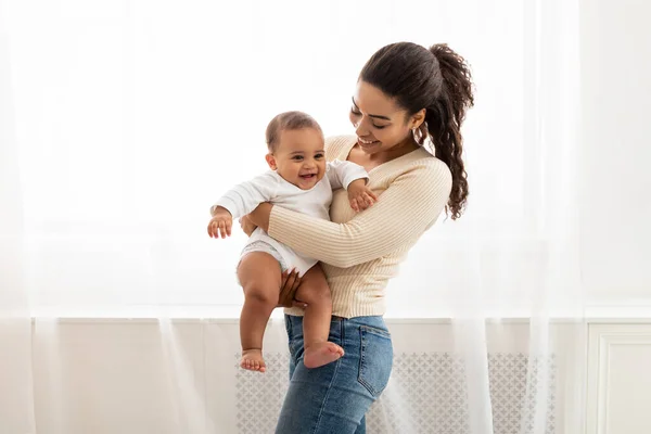 Gioioso nero mamma portare bambino in armi in piedi a casa — Foto Stock