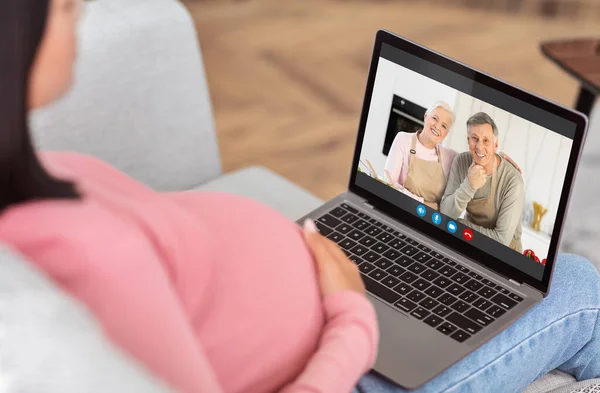 Mujer embarazada irreconocible usando el ordenador portátil en casa, Video chat con padres mayores — Foto de Stock