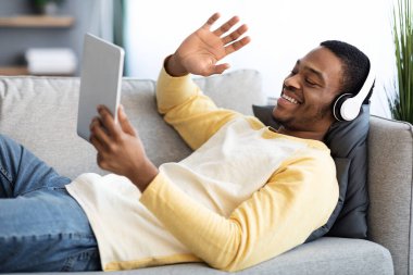 Siyah adam dijital tablet kullanarak arkadaşlarıyla görüntülü görüşme yapıyor.