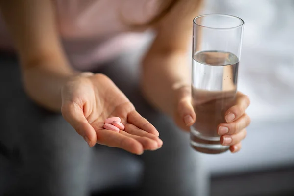 Concepto de prevención y tratamiento del Coronavirus. Vista de cerca de una mujer joven que toma pastillas con agua en casa — Foto de Stock