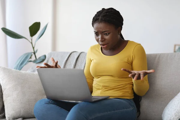 Компьютерные проблемы. Запутавшаяся африканская американка, имеющая проблемы с ноутбуком дома — стоковое фото