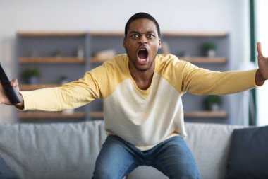 Kızgın siyah adam TV 'de futbol maçı izliyor.