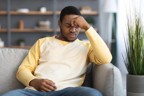 Depressed black guy sitting on couch alone at home — Stock Photo, Image