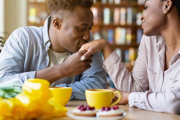 Romantique jeune homme embrassant ses femmes bien-aimées main sur fête Valentines dîner au café confortable — Photo