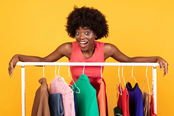 Excitado preto Shopaholic senhora posando perto de vestuário cremalheira, estúdio tiro — Fotografia de Stock