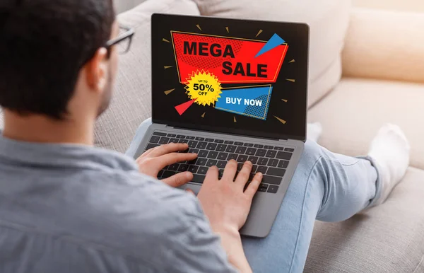 Millennial man använder laptop med mega försäljning annons på skärmen — Stockfoto