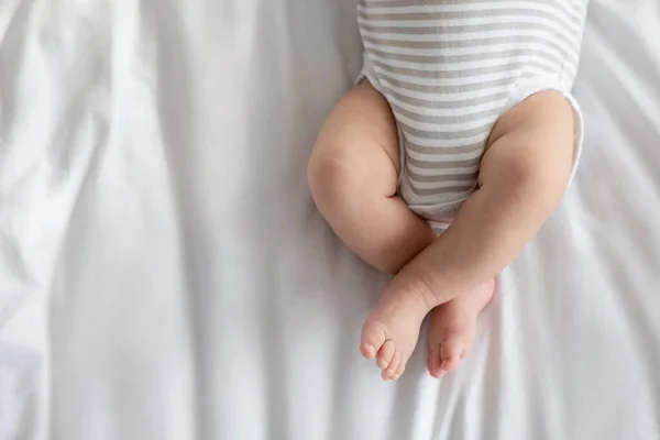 Imagen recortada de pequeño bebé en pañal y traje de cuerpo acostado en la cama —  Fotos de Stock