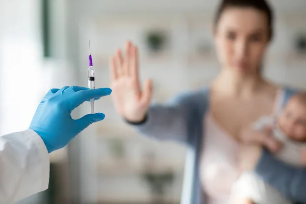 Vaccin Hesitancy. Vrouw met pasgeboren baby weigert spuiten in artsen hand — Stockfoto