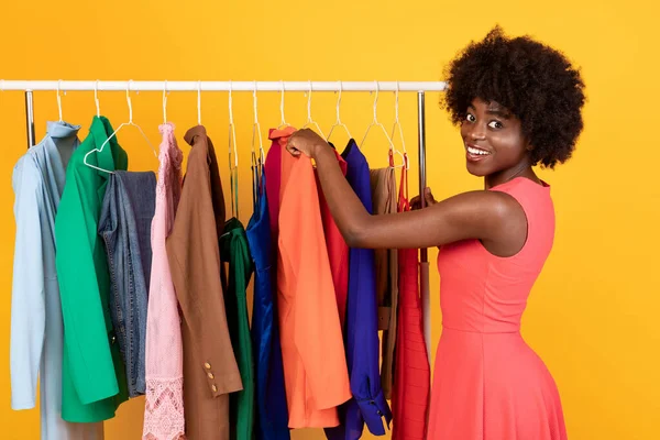 Χαρούμενη Αφρικανή Shopaholic Γυναίκα Επιλέγοντας Ρούχα Αφίσα Πάνω Από Κίτρινο Φόντο — Φωτογραφία Αρχείου