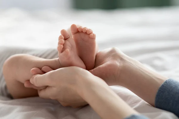 A las madres les importa. Primer plano Shot of Loving Mom sosteniendo los pies del bebé recién nacido en manos —  Fotos de Stock