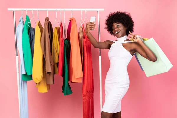Afrikaanse vrouw het maken van selfie op telefoon tijdens het winkelen, roze achtergrond — Stockfoto