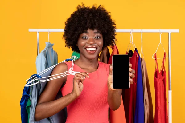 Africano Feminino Mostrando Tela Smartphone Perto Roupa Rack, Fundo Amarelo — Fotografia de Stock