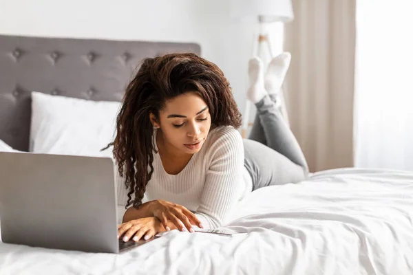 Feliz mujer negra acostada en la cama leyendo el mensaje de texto — Foto de Stock