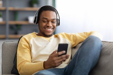 Neşeli Afrikalı Amerikalı adam cep telefonundan video izliyor.