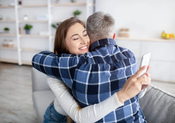 Vício em gadgets ou infidelidade. Mulher madura abraçando marido, preso no smartphone, jogando jogo online, amante de mensagens de texto — Fotografia de Stock