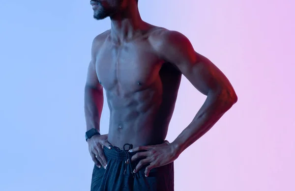 Närbild av sexig ung svart kille med muskulös naken bål poserar i neonljus. Styrketräning koncept — Stockfoto