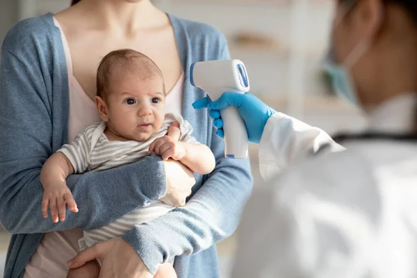 Soins de santé et enfants. Infirmière méconnaissable vérifiant la température du nouveau-né avec le thermomètre infrarouge — Photo
