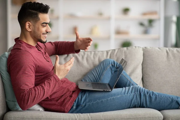 Alegre árabe hombre tener videoconferencia desde casa, utilizando el ordenador portátil — Foto de Stock