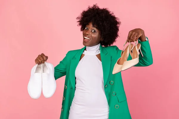 Mulher Africano alegre mostrando sapatos da moda em pé no fundo rosa — Fotografia de Stock