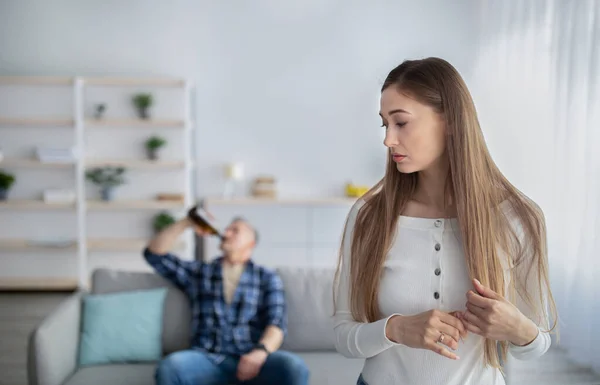 Alcohol addiction and family problems. Sad middle-aged woman looking over her shoulder at her drunk husband — Stock Photo, Image
