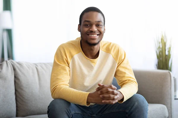 Feliz afroamericano sentado en el sofá en la sala de estar — Foto de Stock