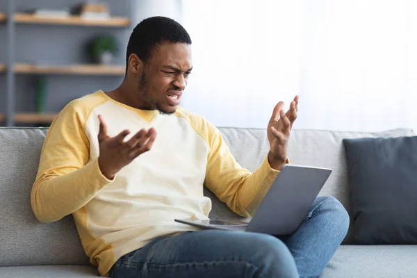 Enojado hombre negro mirando la pantalla del ordenador portátil y el gesto —  Fotos de Stock