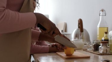 Sağlıklı atıştırmalıklar. Afrikalı Amerikalı anne elmayı kesip küçük kızına veriyor, burnuna dokunuyor.