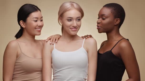 Internationale vriendschap. gelukkig aziatische, Kaukasische en afrikaanse amerikaanse dames lachen samen beige studio achtergrond — Stockvideo