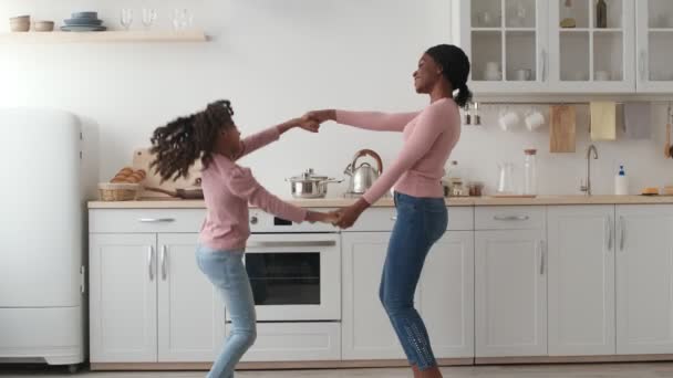 Veselý africký americký matka a dcera tančí společně v kuchyni, baví doma, zpomalený film — Stock video