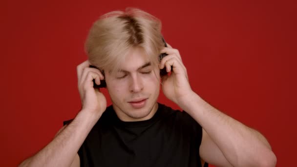 Muziekliefhebber. Jonge blonde gespierde man luisteren naar muziek in grote draadloze hoofdtelefoon, genieten van geluid en lachen — Stockvideo