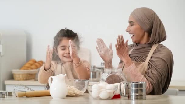 イスラム教徒のお母さんと娘が楽しいベーキング屋内を持って手を拍手 — ストック動画