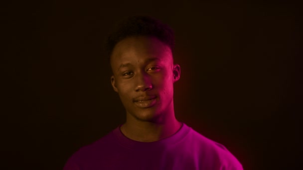 Lovelace concept. Portrait of playful african american man sending blow kiss to camera, posing in pink neon lights — Stock Video